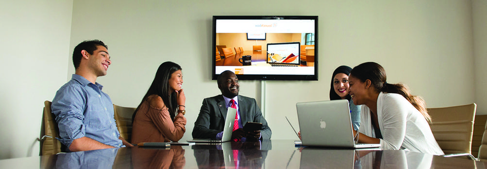 students meeting in the conference room with launchbox website on the screen