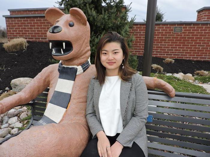 student sitting next to nittany lion statue