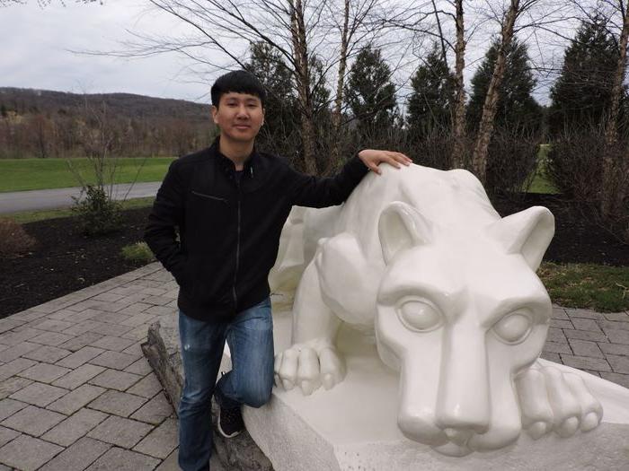 student standing next to nittany lion shrine