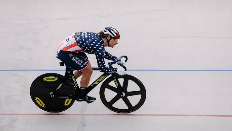 A woman on a bicycle races down a track.